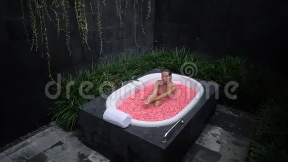 高射炮女孩坐在充满鲜花的浴缸里年轻女子在户外洗澡视频的预览图