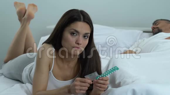 持有避孕套和口服药避孕选择保健的困惑妇女视频的预览图