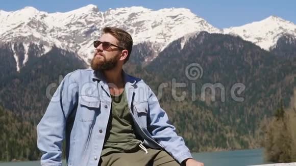 一个长着胡须的人正坐着躺在群山中视频的预览图