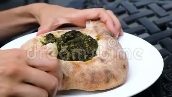 女人吃了一片卡查普里面包混合了菠菜馅料格鲁吉亚民族美食视频的预览图