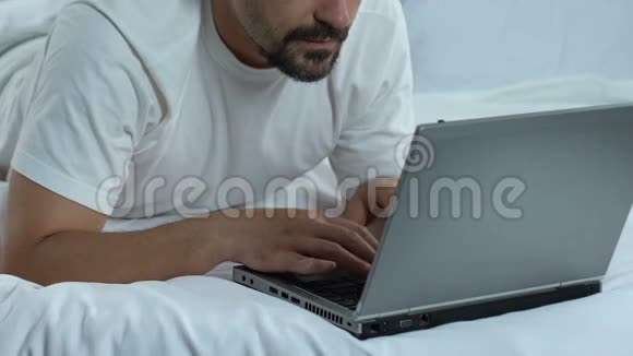 躺在床上打手提电脑的人竖起大拇指自由职业者在网上工作视频的预览图