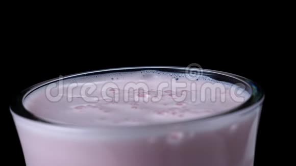 黑色背景下草莓奶昔的特写框架乳粉色鸡尾酒上面有厚厚的泡沫和气泡视频的预览图