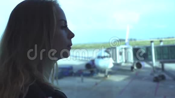女游客在候机室的飞机上寻找机场候机楼窗口女旅行者一边看着窗户视频的预览图