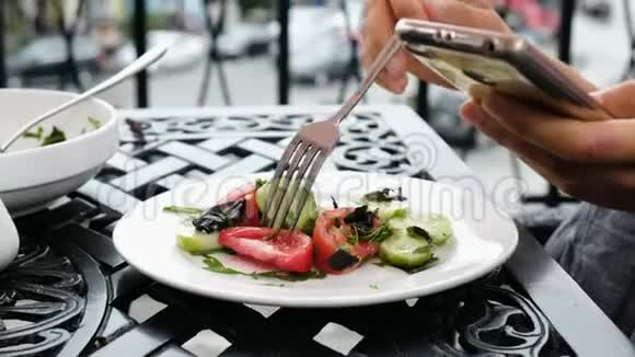 女孩吃沙拉在户外餐馆吃饭时用电话视频的预览图