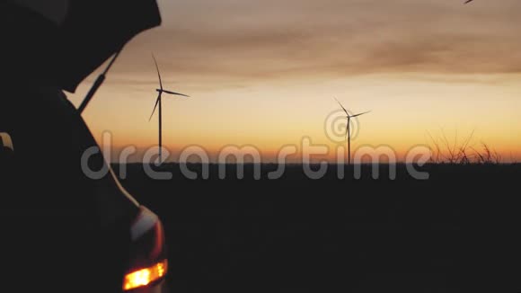 汽车的后备箱在风力发电站和日落的背景下自动关闭视频的预览图