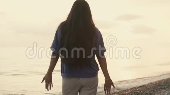 一个年轻的女人站在海边一个长发女士把她的手臂举了起来视频的预览图
