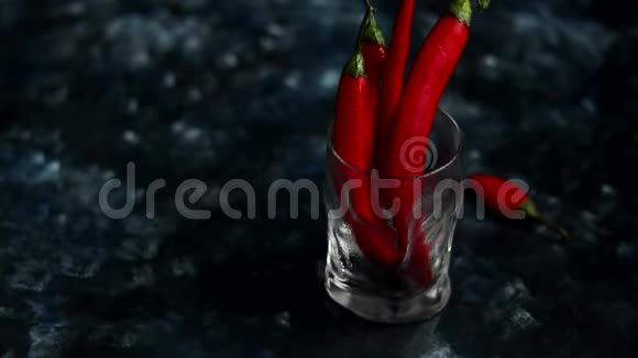 明亮的红色辣椒在透明的玻璃上深蓝色的背景颜色趋势视频的预览图