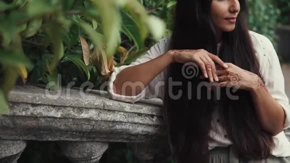 漂亮的晒黑女人在公园里等着一个手上有指甲花纹身的人视频的预览图