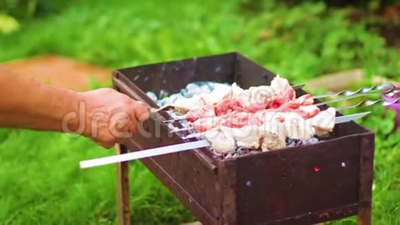 男人他的手把肉放在烤架上视频的预览图