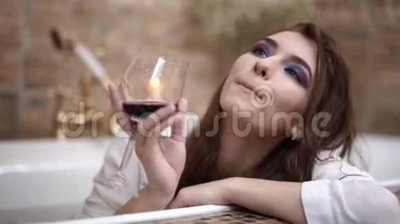 一个忧郁的女孩穿着一件带酒杯的白色衬衫洗了个澡妆容鲜艳视频的预览图