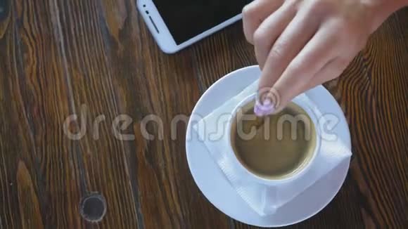 特写女人用勺子手在木桌上的咖啡杯里搅拌糖视频的预览图