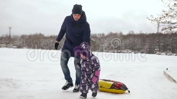 爸爸缓慢地把女儿推到橡皮充气雪管上视频的预览图