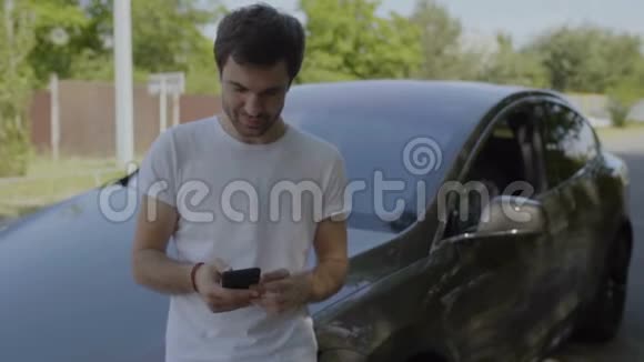 男人微笑着和朋友打电话靠在车上发短信视频的预览图