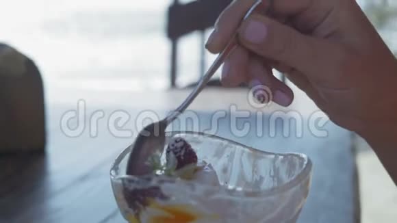 特写镜头女人用勺子手拿一份牛奶甜点和浆果视频的预览图