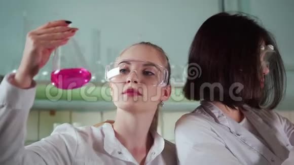 化学实验室两个年轻女子拿着一个装有红色液体的瓶子视频的预览图