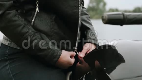一个坐在摩托车上的女孩穿上了她的皮夹克自行车系皮夹克4k慢动作视频的预览图