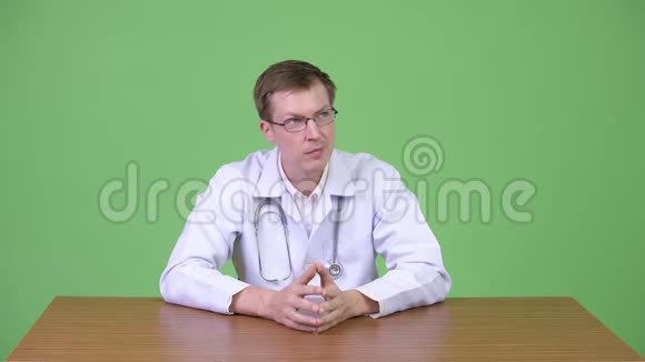年轻快乐男医生坐着思考的画像视频的预览图