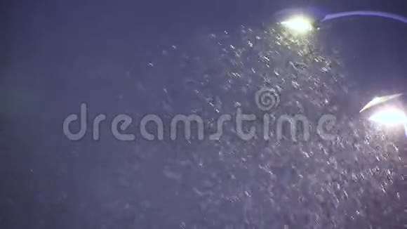在路灯的背景下在冬天的雪上降雪视频的预览图