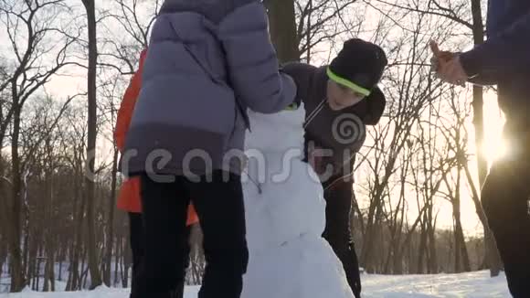 4个男孩慢动作在冬季公园堆雪人视频的预览图