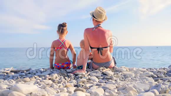 妈妈和两个幼儿坐在沙滩上看海视频的预览图