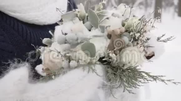 冬天的女孩戴着手套在寒冷的雪天带着一束美丽的花视频的预览图