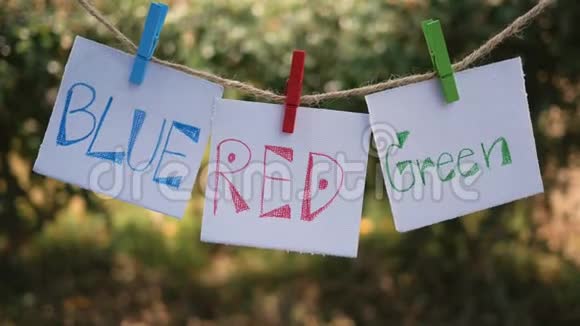 纸用手写字颜色蓝色红色绿色挂在一根绳子上用木夹在自然视频的预览图