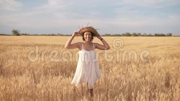 夏天麦田里美丽的黑发卷发女士微笑着戴着草帽摆姿势正面观点视频的预览图