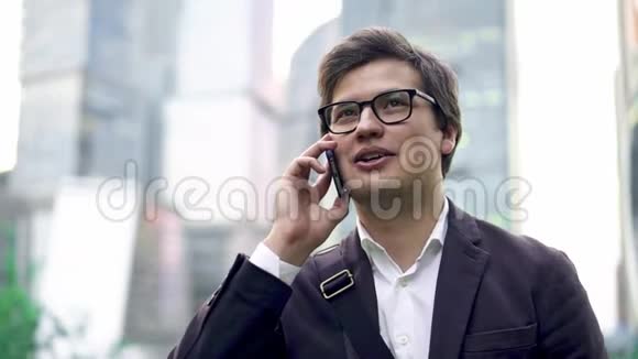 自信的年轻商人在莫斯科市用他的电话交谈倾斜下来视频的预览图