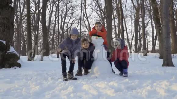 冬天公园里四个穿着紧身衣的男孩在堆雪人的时候视频的预览图