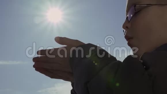 小男孩用太阳把手中的雪花吹在蓝天上视频的预览图