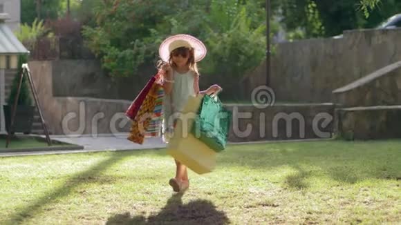 购物之旅时尚的戴墨镜和帽子的小女孩购物者在参观商店后用袋子购物视频的预览图