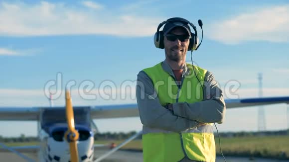 一位微笑的飞行员正站在田野的双平面附近视频的预览图