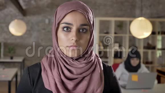 戴着头巾的年轻穆斯林妇女直视镜头的肖像严肃的两个在现代工作的漂亮妇女视频的预览图