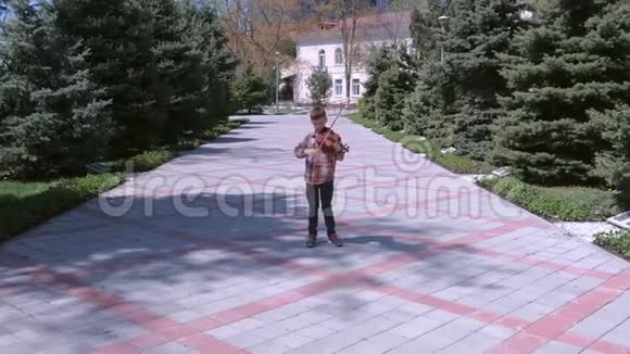小男孩正在拉小提琴站在城市街道上的小巷里视频的预览图