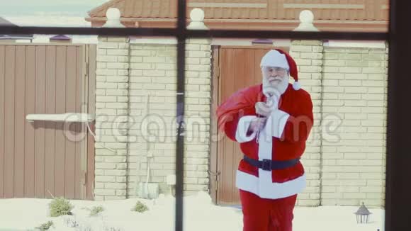 圣诞老人拿着一袋礼物走到家里视频的预览图