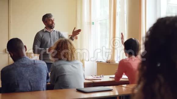 好奇的学生举手问问题她有经验的老师用友好的微笑回答她视频的预览图
