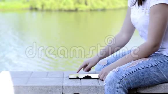 女孩在湖边使用数码平板电脑视频的预览图