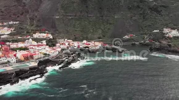 空中射击火山石海岸的冻结熔岩打击蓝色的海浪与白色泡沫一个小镇视频的预览图
