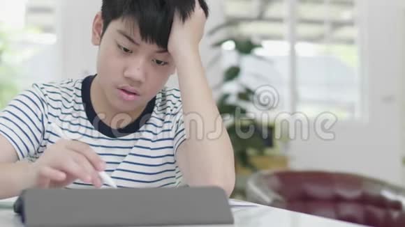 脾气不好的亚洲男孩用平板电脑做作业来查找资料视频的预览图