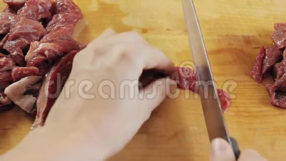女人用刀子在木板上把生牛肉切成小块视频的预览图