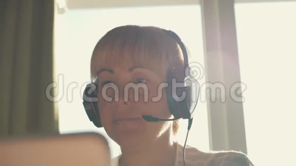 戴着耳机的女商人在阳光下在互联网上交流视频的预览图