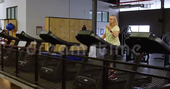 在健身室4k跑步机上做运动的女人视频的预览图
