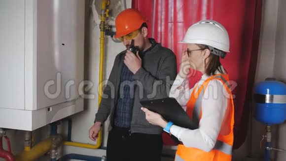 男工程师和女检查员检查锅炉房设备的可操作性女人把数据输入视频的预览图