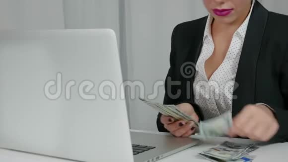 快乐女人从她的笔记本电脑里数美元丰度概念视频的预览图
