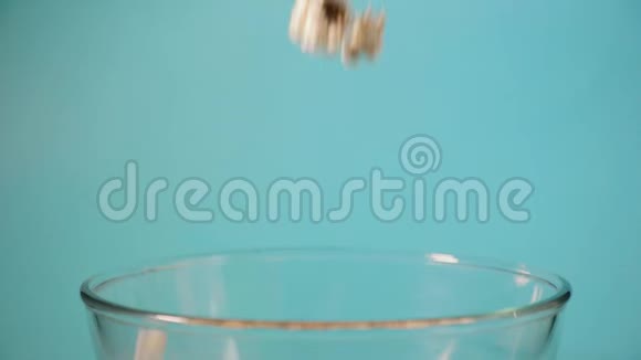 爆米花被倒入一个蓝色背面的透明玻璃碗里视频的预览图