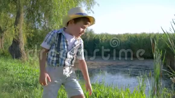 阳光明媚的一天戴着草帽的口渴男孩喝着水壶里的水视频的预览图