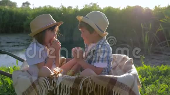 农村生活戴草帽的小男孩和小女孩在阳光下坐在手推车里吃水果视频的预览图