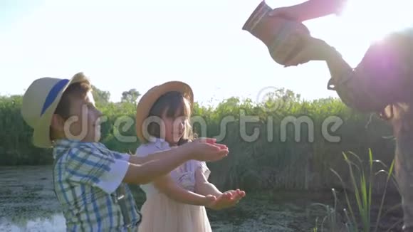 父母的照顾妈妈把水从一个水壶里倒进孩子的手里在湖边的露天视频的预览图