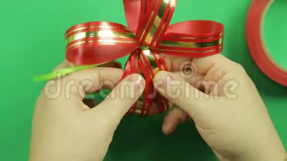 女人双手伸直红丝带礼物蝴蝶结的花瓣并给它形状绿色背景视频的预览图