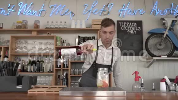 一个英俊的年轻酒保在酒吧柜台做一杯新鲜的凉爽的红色柠檬水视频的预览图